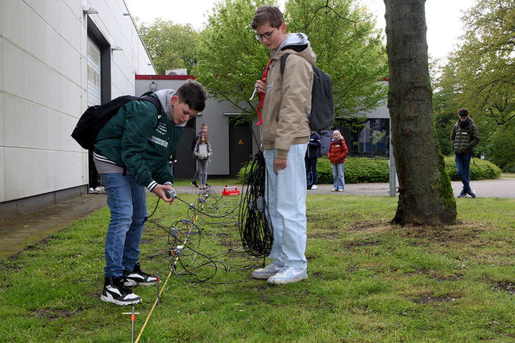 Schüler bauen eine kleine geoelektrische Messstrecke auf, um die elektrische Leitfähigkeit des Untergrunds zu bestimmen.