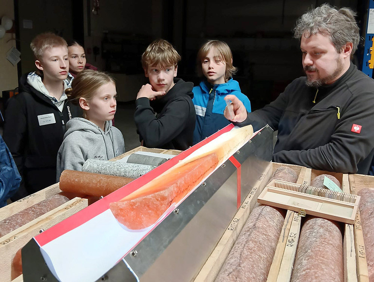 Das Bild zeigt Schülerinnen und Schüler, die sich einen Salzbohrkern zeigen lassen.