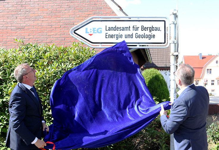 Das Foto zeigt Zur Geburtstagsfeier enthüllen LBEG-Präsident Carsten Mühlenmeier (li.) und Meppens Bürgermeister Helmut Knurbein, die ein Tuch von einem neuen Straßenschild ziehen.